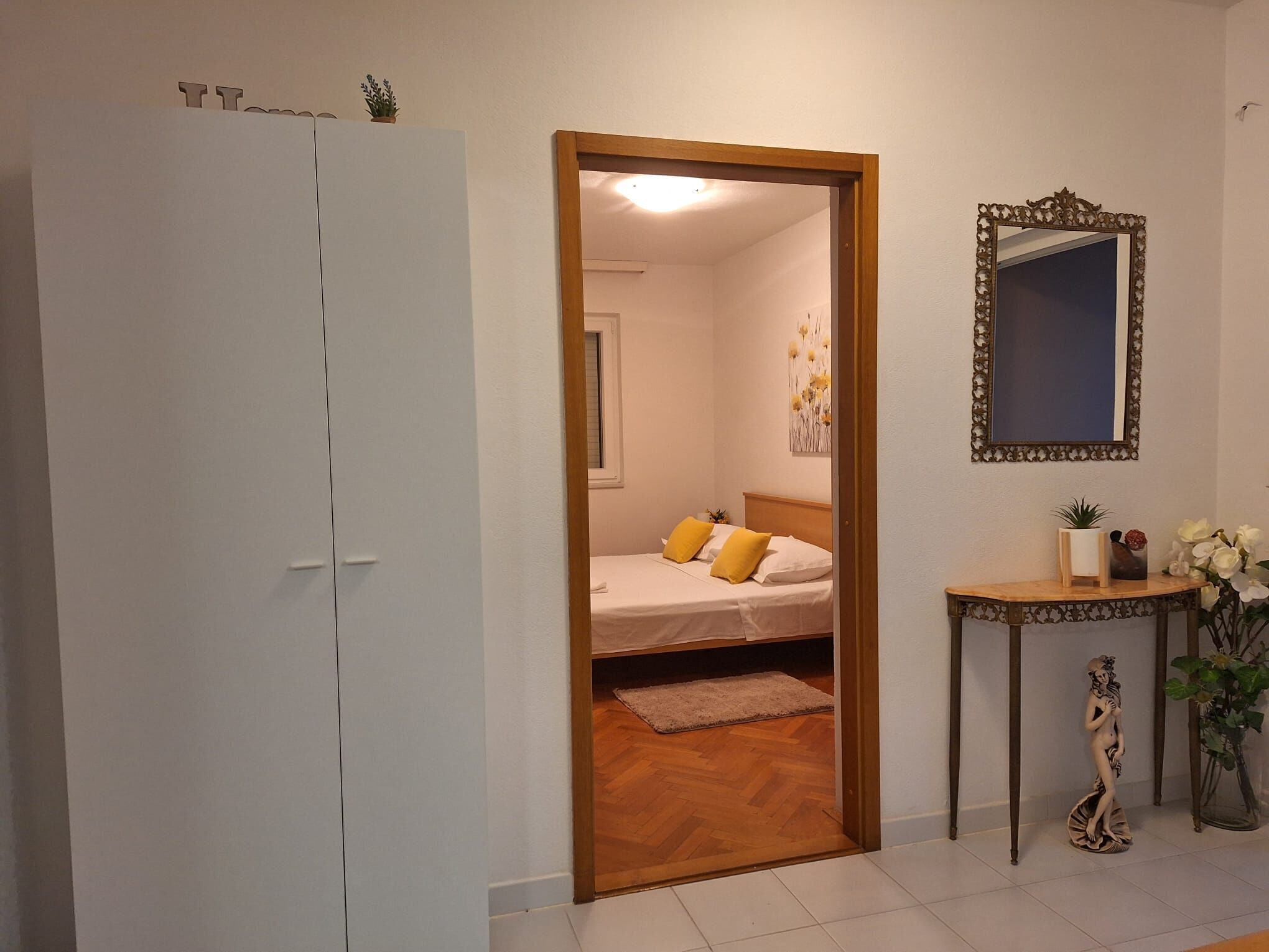 A bedroom with a bed, a bedside table, a mirror, and a wardrobe.