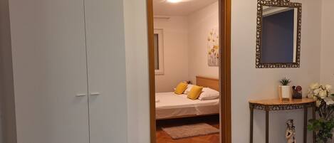 A bedroom with a bed, a bedside table, a mirror, and a wardrobe.