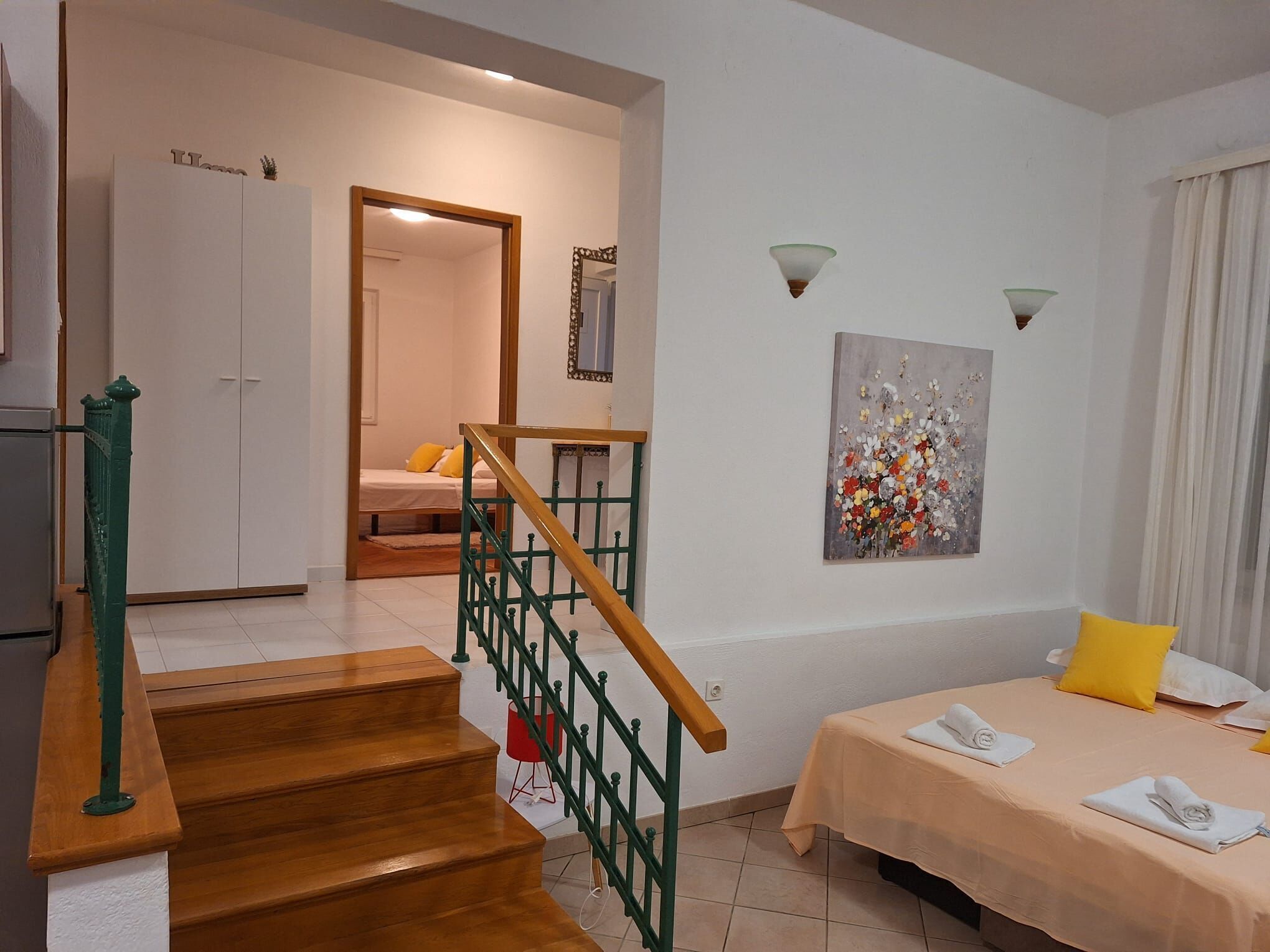 Ein Schlafzimmer mit einem Bett, einem Gemälde, einer Treppe und einem Kleiderschrank.
