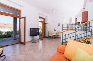 A spacious living area with a TV, a dining table, and a staircase. - Apartments Ornela (Split)