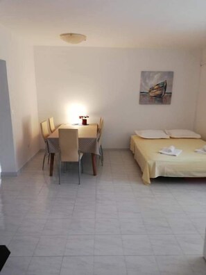A small, clean room with a bed, a dining table with chairs, and a painting on the wall. - Apartments Ornela (Split)