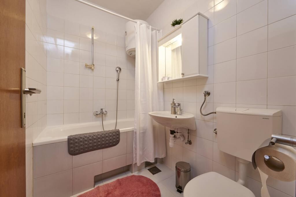 Un bany modern amb banyera, dutxa, vàter i rentapans.
