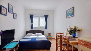 A bedroom with a bed, a desk, a chair, a TV, and a window with curtains. - Apartments Villa Sarajevo (Vodice)