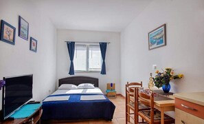 A bedroom with a bed, a desk, a chair, a TV, and a window with curtains. - Apartments Villa Sarajevo (Vodice)