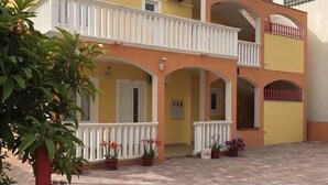 A two-story building with a yellow facade, white balconies, and a paved courtyard. - Apartments Villa Sarajevo (Vodice)