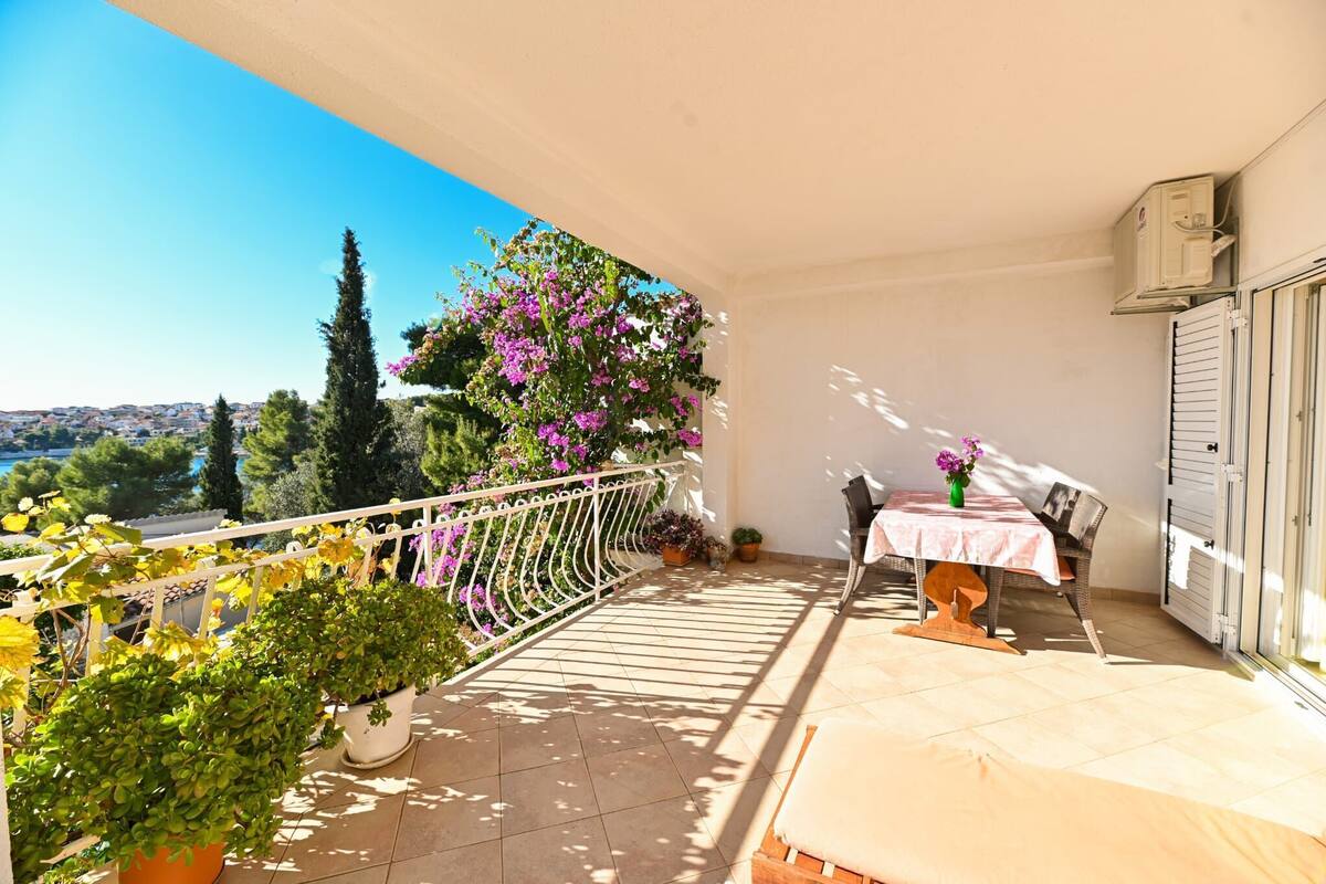 A balcony with a table and chairs, potted plants, and a view of the landscape.