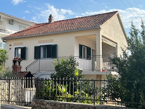 Ein zweistöckiges Haus mit Ziegeldach, Balkon und Steinwand.