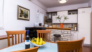 A dining area with a table, chairs, a bowl of fruit, and a wine bottle. - House Holiday House (Okrug)