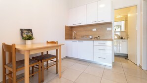 Una cocina moderna con armarios blancos, una mesa de madera y sillas.