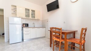 Una cocina con armarios blancos, microondas, fregadero y una mesa de comedor con sillas.