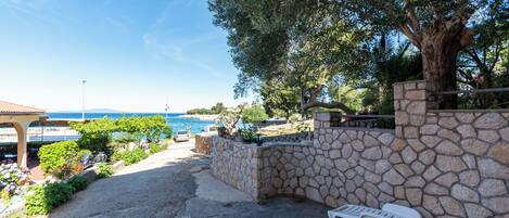 A stone wall, a white lounge chair, and a view of the sea.