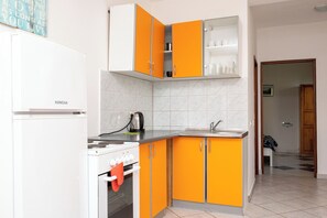 A kitchen with white and orange cabinets, a white stove, and a sink. - Apartments Seafront Oasis (Ston)