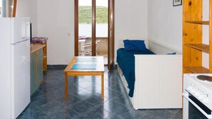 Una cocina compacta con refrigerador, estufa y una mesa con mantel individual azul.