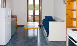 Una cocina compacta con refrigerador, estufa y una mesa con mantel individual azul.