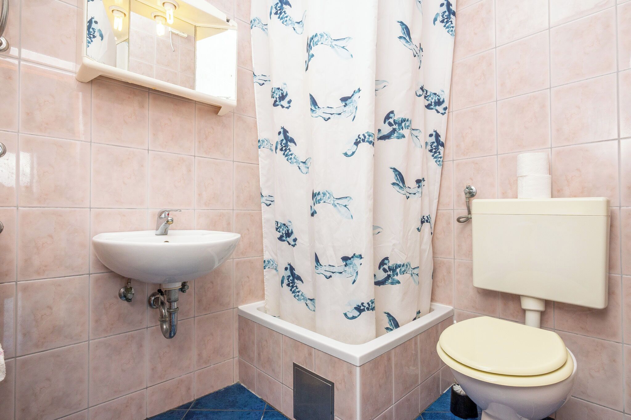 Un baño con lavamanos, inodoro, cortina de ducha y paredes de azulejos.