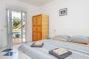 Un dormitorio con cama, armario, puerta corrediza de vidrio a un patio y un cuadro en la pared.