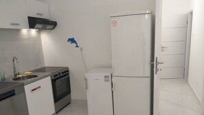 A compact kitchen with a sink, stove, oven, and a white refrigerator. - Apartments and Rooms Rakic (Mali Losinj)