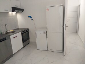 A compact kitchen with a sink, stove, oven, and a white refrigerator. - Apartments and Rooms Rakic (Mali Losinj)