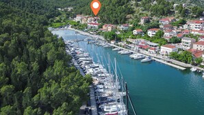 An aerial view of a marina with boats docked along a waterfront, surrounded by residential buildings and dense greenery.
