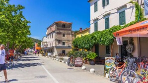 A street with buildings, a bike rental sign, and a sign for 'SOBE ZIMMER GAMERE ROOMS'. - Apartment Skatula Skradin (Skradin)