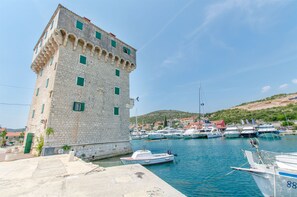 A historic stone building with multiple windows and a port with several boats docked. - Apartments Mirkovic (Marina)