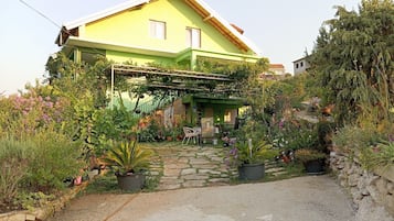 A green house with a stone pathway leading to a covered porch.