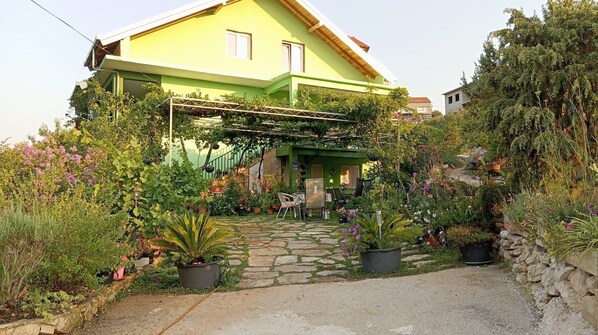 A green house with a stone pathway leading to a covered porch. - Apartments Mirkovic (Marina)