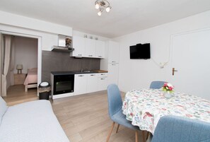 Ein kompaktes Hotelzimmer mit Küchenzeile, einem Essbereich mit Tisch und Stühlen sowie einem Bett.