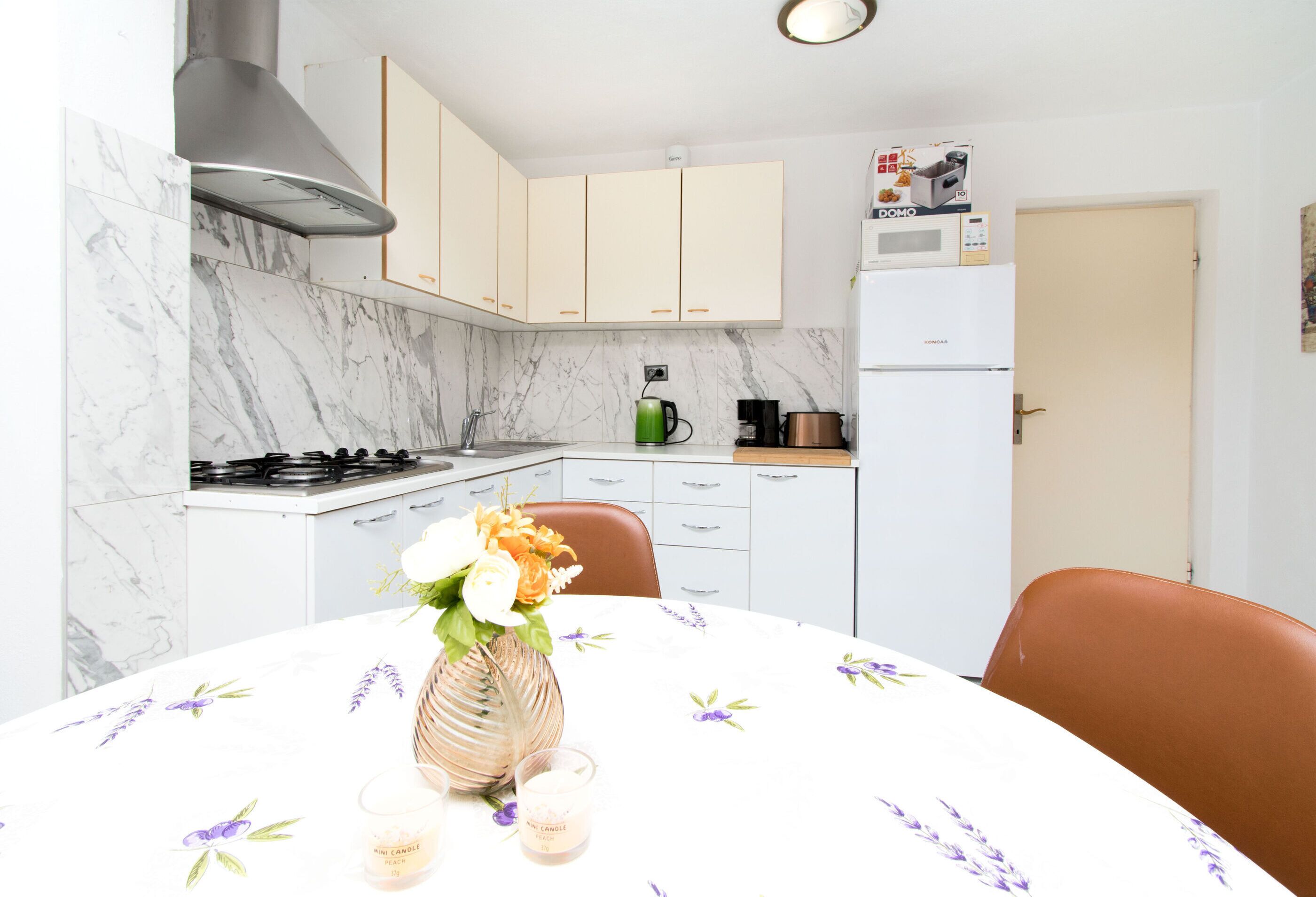 A kitchen with white cabinets, a stove, a microwave, and a refrigerator.