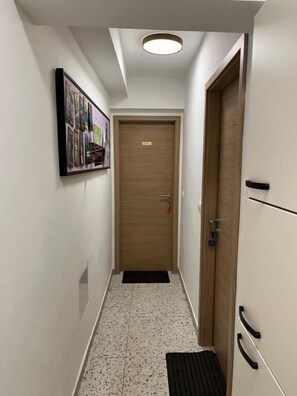 A narrow hallway with a wooden door, a framed photo collage on the wall, and a black mat at the entrance. - Apartments Angels Anna i Marlen (Pula)