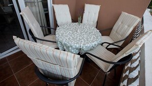 A round table with a floral tablecloth surrounded by six striped chairs. - Apartment Armina (Vodice)