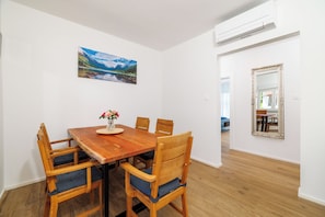 Ein Essbereich mit Holztisch und Stühlen, einem Bild an der Wand und einem Spiegel.