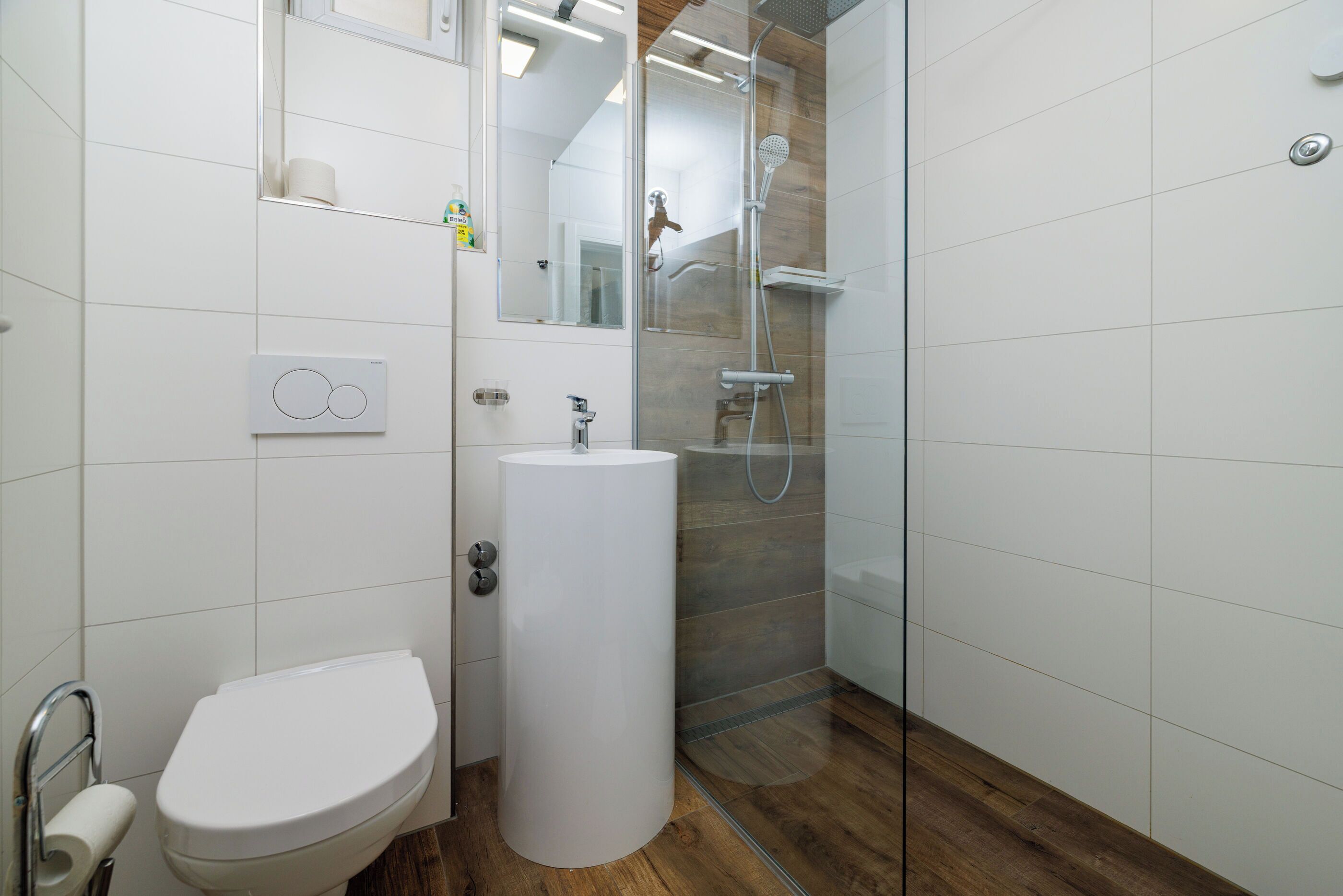 A modern bathroom with a toilet, sink, and glass-enclosed shower.