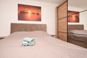 Ein Hotelzimmer mit Bett, einem Holzschrank und einem Sonnenuntergangsbild an der Wand.