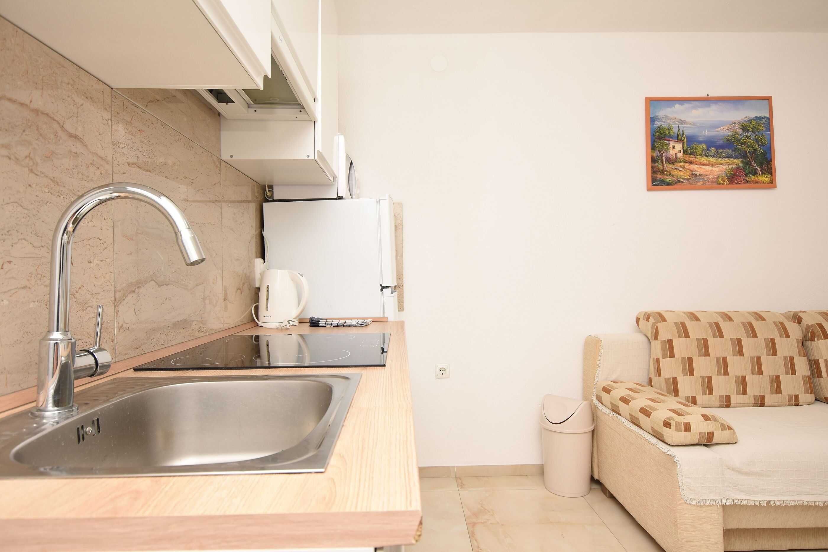 A kitchen with a stainless steel sink, a microwave, and a white cabinet.