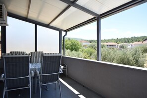 A covered outdoor area with a table and chairs, a view of a residential area, and a clear sky. - Apartments Relax (Obrovac)
