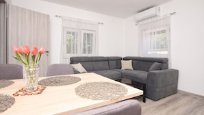 A modern living room with a grey sofa, a wooden coffee table, and a vase with flowers. - Apartments Relax (Obrovac)
