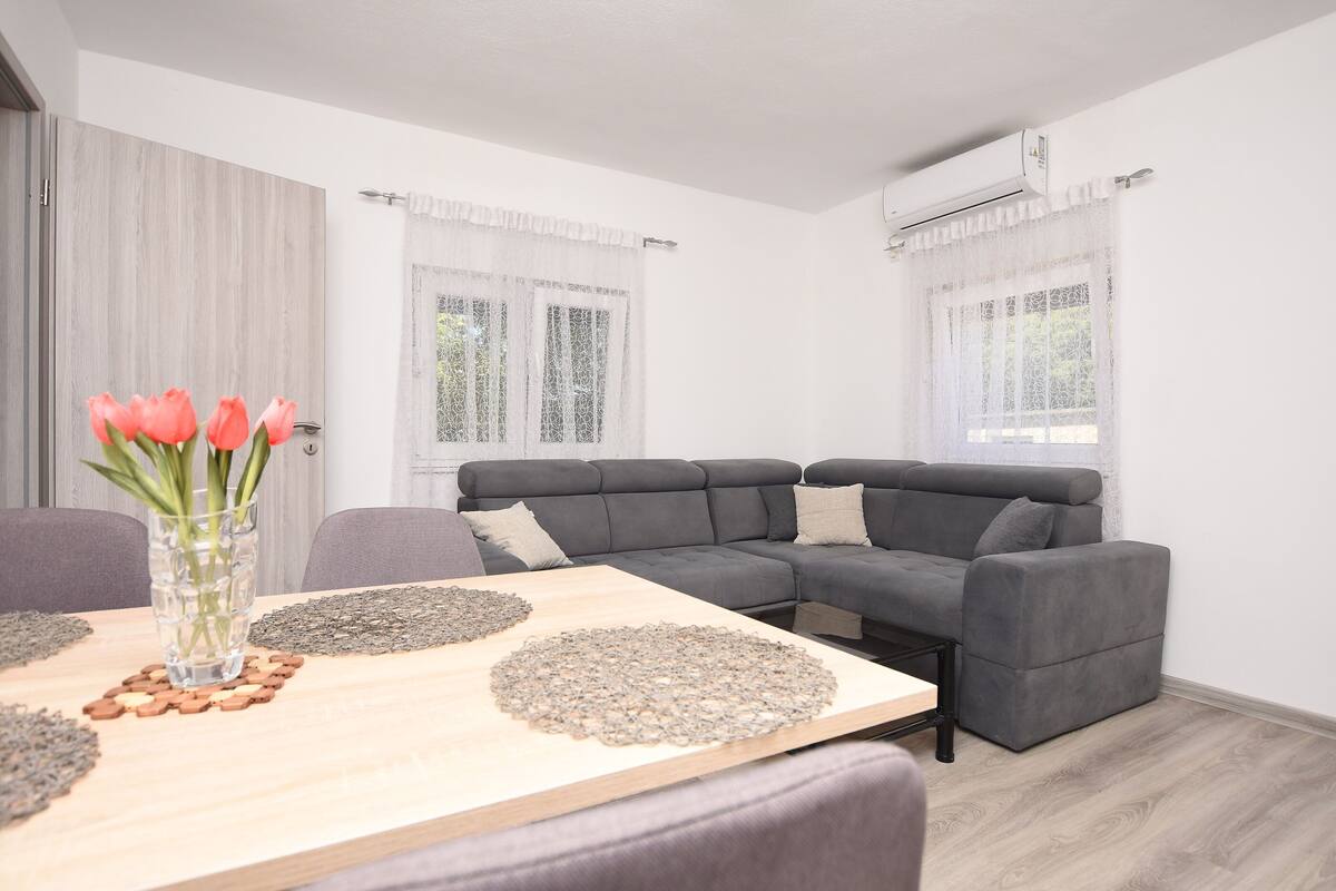 Un salon moderne avec un canapé gris, une table basse en bois et un vase rempli de fleurs.