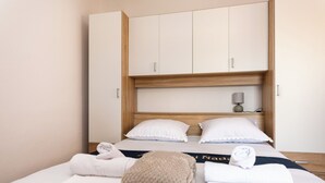 Hotellihuone, jossa on sänky, puinen vaatekaappi ja yöpöytä, jossa on lamppu.
