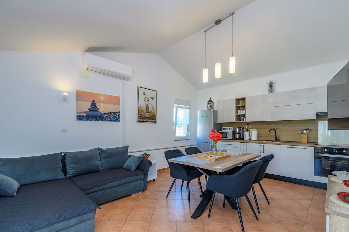 A modern kitchen with a dining area, a sofa, and a painting on the wall.