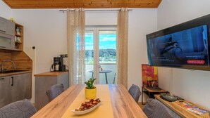Ett modernt kök med ett träpanelat tak, ett matbord med en gul bordsduk och en tv som är monterad på väggen.