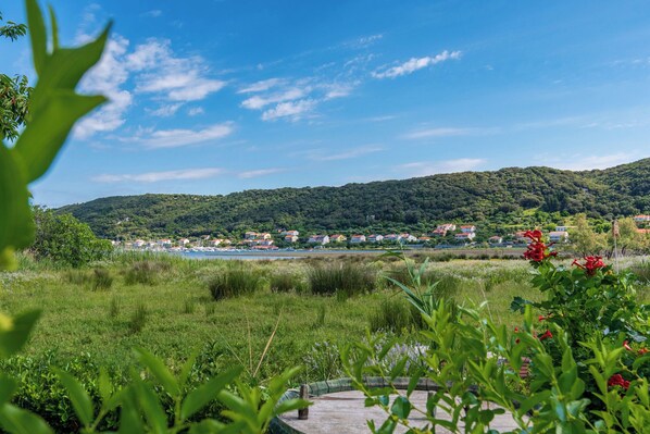 A coastal landscape with a view of a town, green hills, and a body of water. - Apartments Angela (Rab)