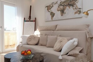 Ein Wohnzimmer mit einer Couch, Kissen, einem Couchtisch mit Obst, einer Weltkarte und einer Gitarre.