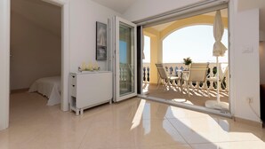 A room with a bed, a white dresser, a glass door leading to an outdoor seating area with a table and chairs. - Apartments VV Adriatic Panorama (Vodice)