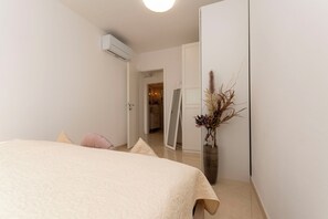 Ein Schlafzimmer mit einem Bett, einer Vase mit Trockenpflanzen und einer Tür zu einem anderen Raum.