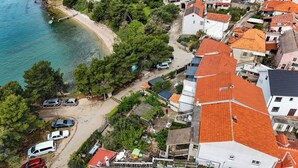 Ett flygbildsbild av ett bostadsområde vid kusten med hus, en strand och parkerade bilar.