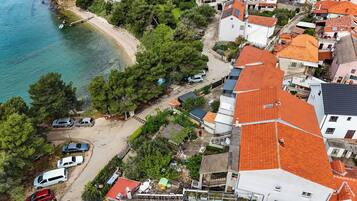 Vista aérea de uma área residencial costeira com casas, praia e carros estacionados.