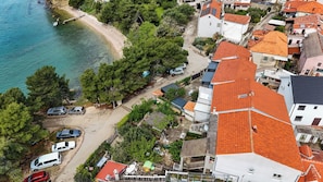 Luftaufnahme einer Küstenwohngegend mit Häusern, einem Strand und geparkten Autos.