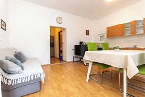 A compact living space with a sofa, dining table, chairs, and a kitchenette. - Apartment Kalma (Zadar)