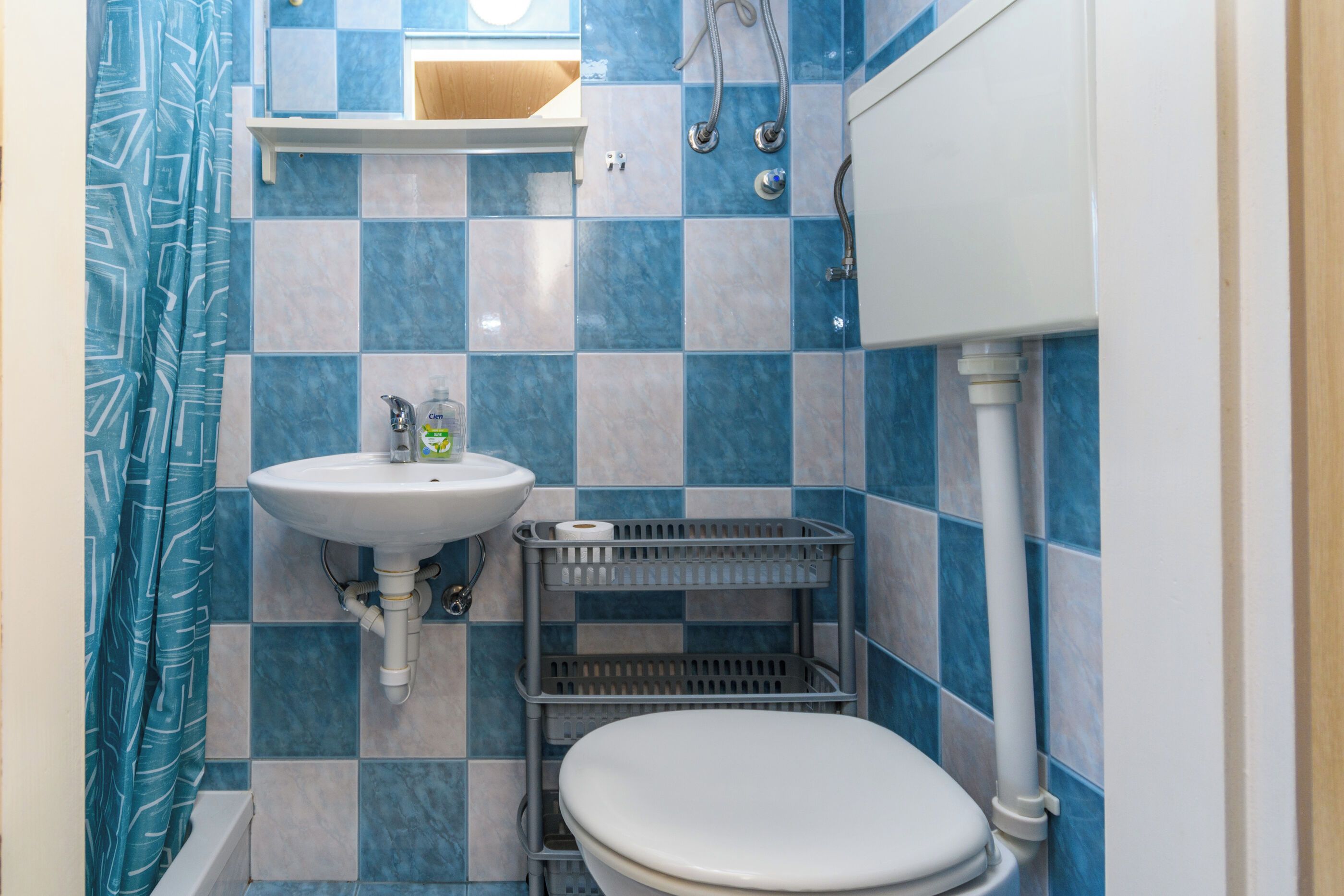 Une petite salle de bain avec un lavabo blanc, des toilettes et une douche.